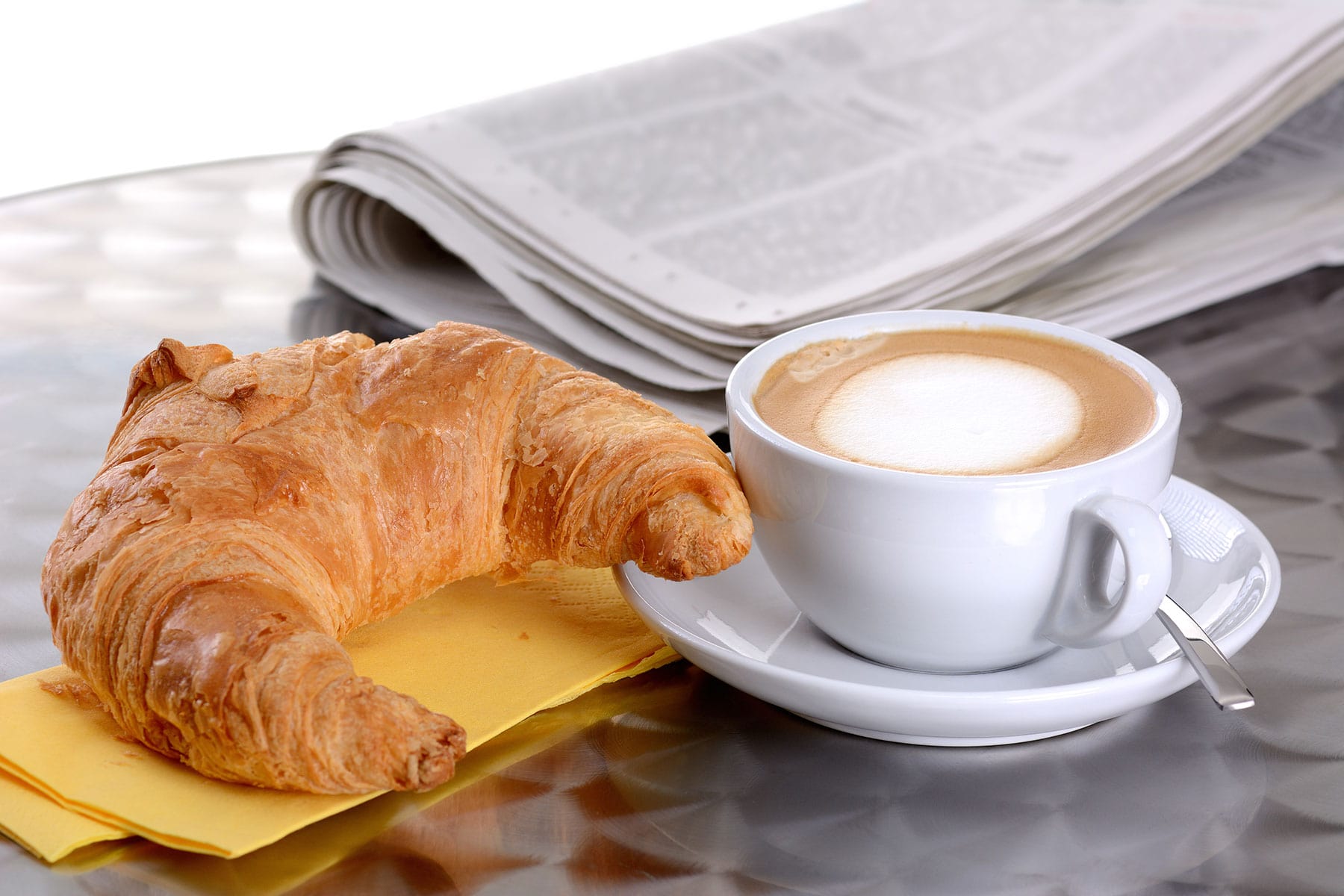 Bild mit Crossant und Kaffee sowie Zeitung